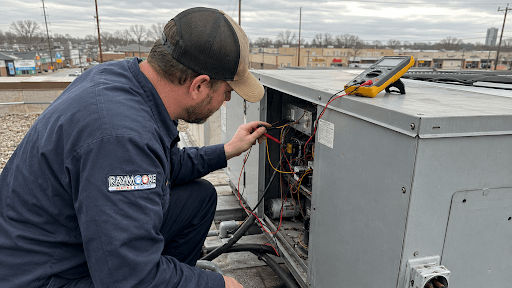 Commercial RTU maintenance technician inspecting an open rooftop unit access panel on a flat commercial building roof in Indianapolis.
